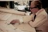 Frank Lloyd Wright reviewing plans at a drafting table. 